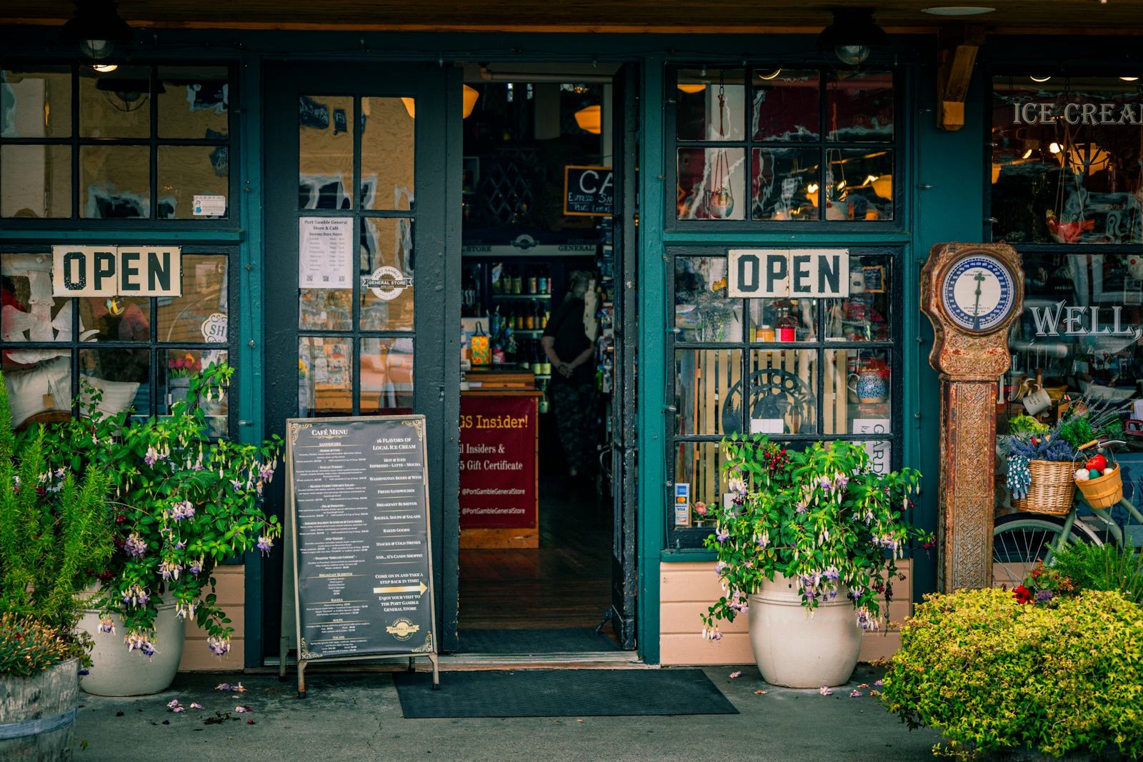 A small shop front with open signs and potted plants